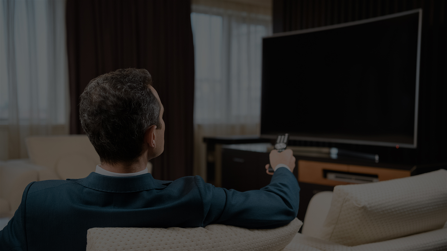 Image of a businessman watching TV in hotel room